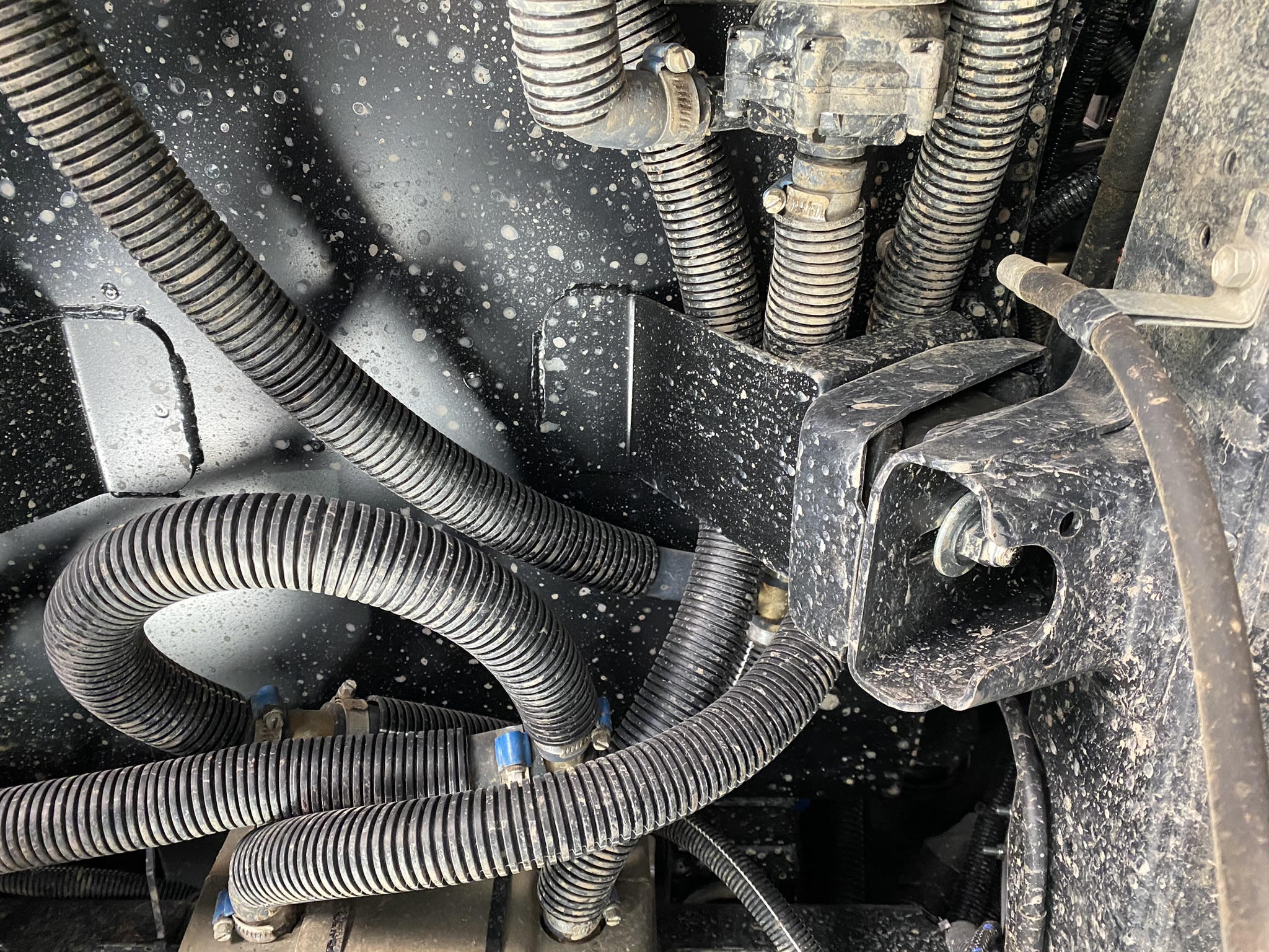 Split convoluted conduit protecting cable looms in a vehicle underside application — real-world cable management in a harsh environment
